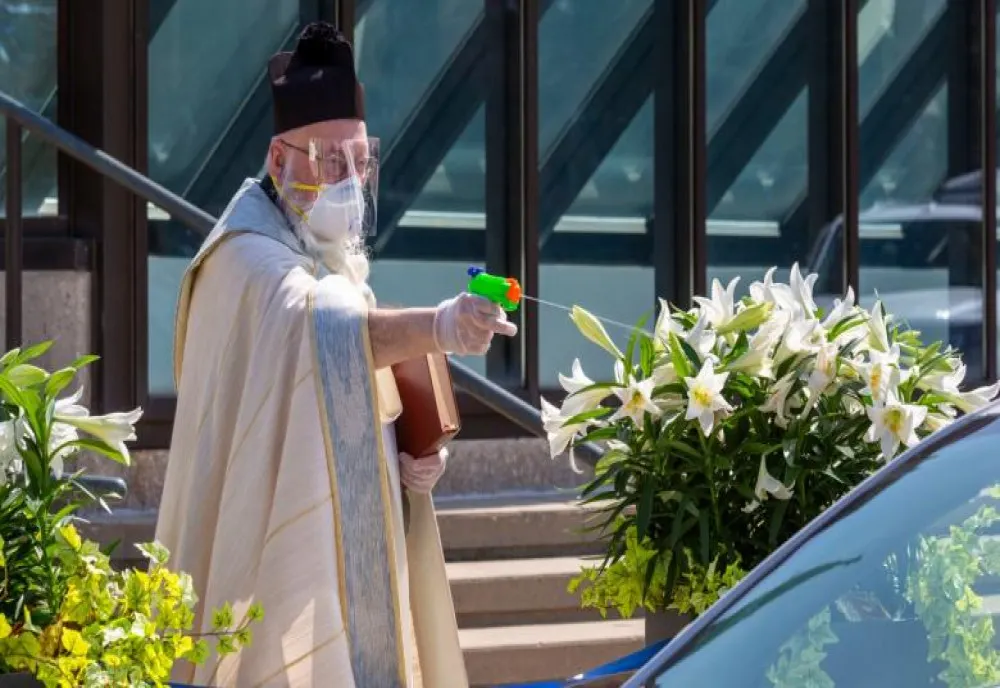   Galerie Foto  Un preot a folosit un pistol de jucărie pentru a stropi credincioșii cu apă sfințită, respectând distanțarea fizică 